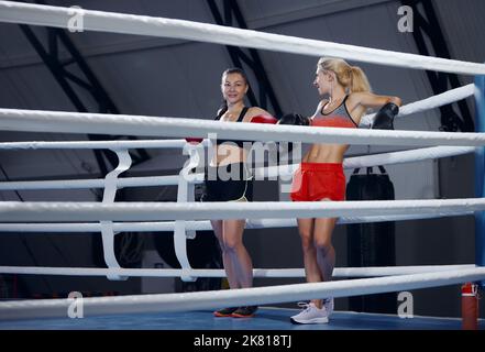 Junge Sportlerinnen, Profiboxerinnen und Kickboxerinnen erholen sich nach hartem Training im Sportstudio. Konzept von Sport, Training, aktiv und gesund Stockfoto