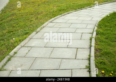 Weg im Park. Fliesenpfad durch den Park. Details zur Fußgängerzone. Ort zum Wandern. Fliesen aus Stein. Stockfoto