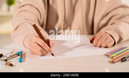 Beschnittene Ansicht der Frau, die auf Papier in der Nähe von Zeichnung Kompass und Buntstifte zu Hause schreiben, Stock Bild Stockfoto