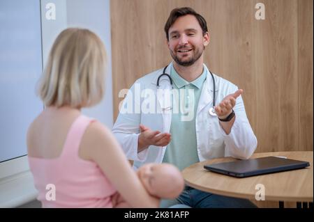 Freundlicher junger Kinderarzt, der Patienten in seinem Büro empfängt Stockfoto