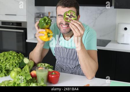 Mann spielt mit grünen Paprika in der Küche Stockfoto