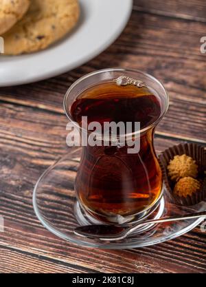 Frisch gebrühter schwarzer türkischer Tee mit Keksen auf dem Holztisch Stockfoto