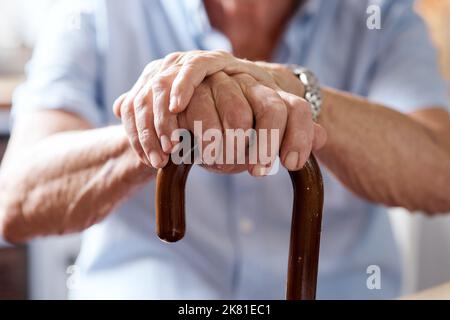 Ich habe die Geburt all dessen gesehen, was jetzt nicht ist. Nahaufnahme eines nicht erkennbaren älteren Mannes, der zu Hause an einem Stock festhält. Stockfoto