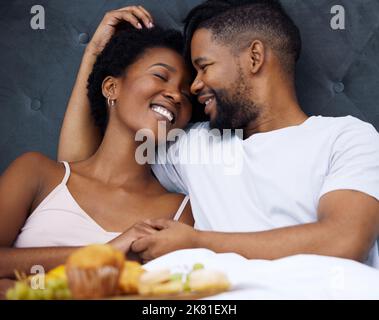 Das gemeinsame Frühstück macht den Sonntag noch besser. Ein glückliches junges Paar genießt das Frühstück im Bett zusammen zu Hause. Stockfoto