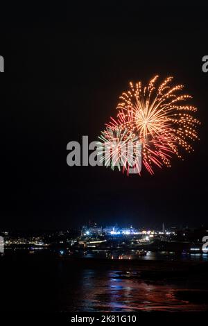 Feuerwerk von den britischen Feuerwerkmeisterschaften explodiert über der beleuchteten Stadt Plymouth, Cornwall. Stockfoto