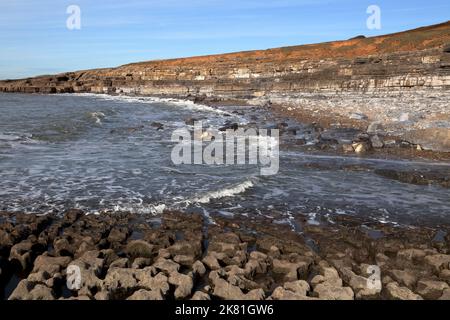 Eine große Bucht in der Nähe des bekannten Ogmore vertieft sich, zeigt Felsschichten und riesige zufällige Felsen mit der Flut auf dem Weg in. Stockfoto