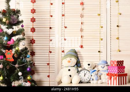 Schneemänner und Teddybären in der Nähe von Uhr und Weihnachtsbaum. Stockfoto