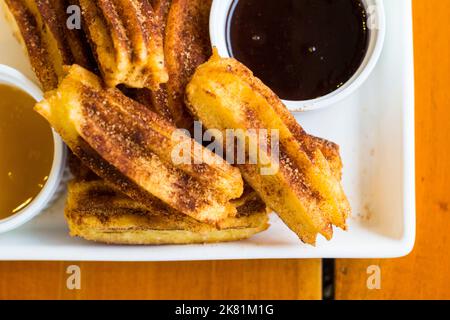 Ein Gericht aus kurzen Churros mit einer Karamell- und Schokoladensauce in Cebu, Philippinen Stockfoto