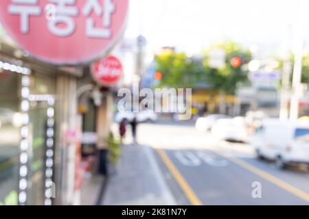 Verschwommener Blick auf die Seoul Street mit Geschäften, Straßen, Autos und Gebäuden. Kann als Hintergrund verwendet werden. De fokussiertes Bild der Hauptstadt von Südkorea. Stockfoto