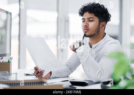 HES gründlich, wenn es um die Planung kommt. Ein junger Geschäftsmann geht durch Papierkram in einem Büro. Stockfoto