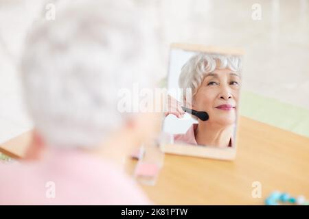 Japanische ältere Frau, die Make-up anwendet Stockfoto
