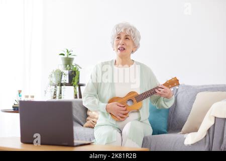 Japanische ältere Frau spielt Ukulele Stockfoto