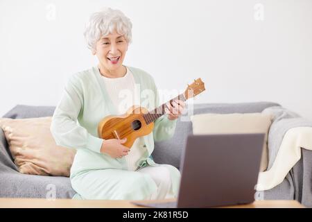 Japanische ältere Frau spielt Ukulele Stockfoto