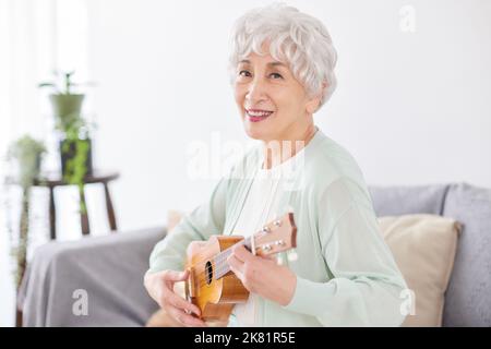 Japanische ältere Frau spielt Ukulele Stockfoto