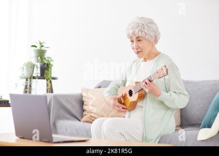 Japanische ältere Frau spielt Ukulele Stockfoto