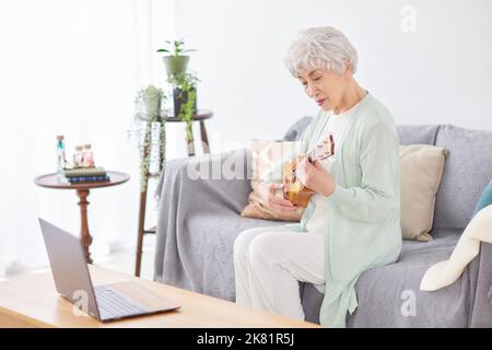 Japanische ältere Frau spielt Ukulele Stockfoto