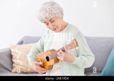 Japanische ältere Frau spielt Ukulele Stockfoto