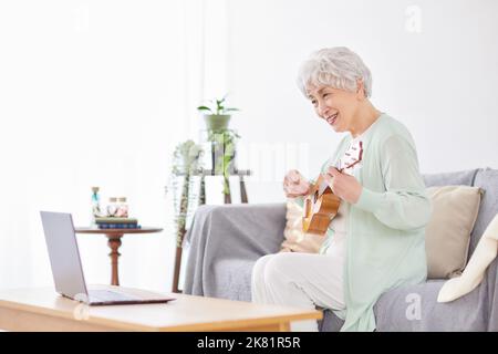 Japanische ältere Frau spielt Ukulele Stockfoto