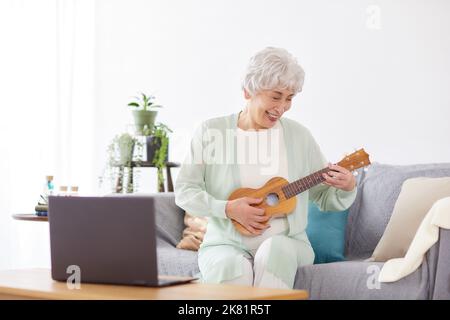 Japanische ältere Frau spielt Ukulele Stockfoto