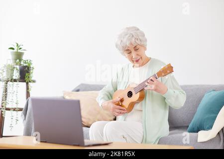 Japanische ältere Frau spielt Ukulele Stockfoto