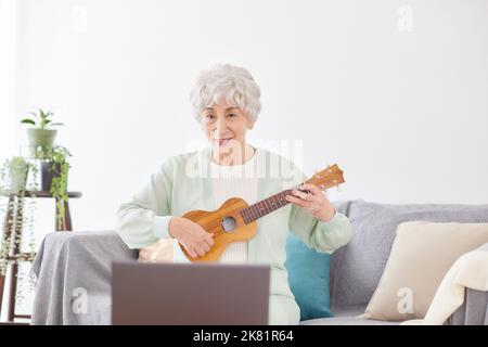 Japanische ältere Frau spielt Ukulele Stockfoto
