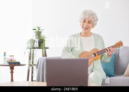 Japanische ältere Frau spielt Ukulele Stockfoto