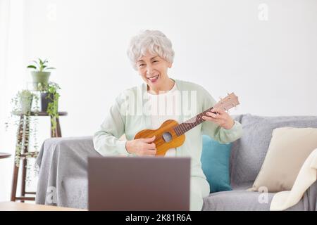 Japanische ältere Frau spielt Ukulele Stockfoto