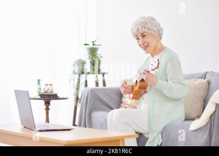 Japanische ältere Frau spielt Ukulele Stockfoto