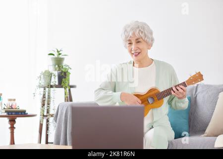 Japanische ältere Frau spielt Ukulele Stockfoto
