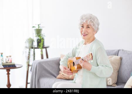 Japanische ältere Frau spielt Ukulele Stockfoto