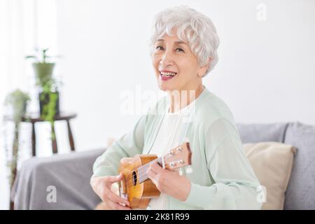 Japanische ältere Frau spielt Ukulele Stockfoto