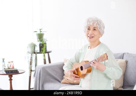 Japanische ältere Frau spielt Ukulele Stockfoto