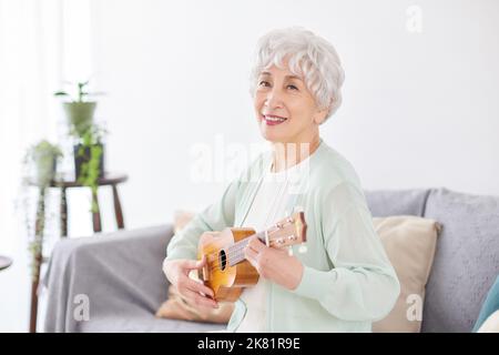 Japanische ältere Frau spielt Ukulele Stockfoto
