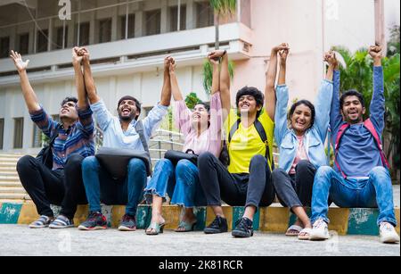 Angeregte Gruppe von Studenten, die nach den Prüfungen auf dem College-Campus gegenseitig die Hände halten, um zu rufen - Konzept der Freundschaft, Bindung, Glück Stockfoto