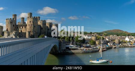 Conwy, Vereinigtes Königreich - 27. August 2022: Panoramablick auf das Conwy Castle und die Brücke mit der ummauerten Stadt und dem Hafen dahinter Stockfoto