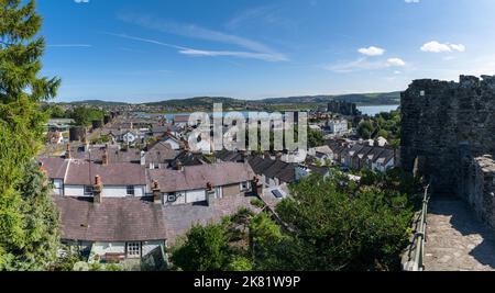 Conwy, Vereinigtes Königreich - 27. August 2022: Blick auf die von Mauern umgebene walisische Stadt Conwy mit dem mittelalterlichen Schloss und dem Fluss Conwy dahinter Stockfoto