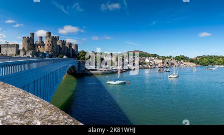 Conwy, Vereinigtes Königreich - 27. August 2022: Blick auf das Conwy Castle und die Brücke mit der ummauerten Stadt und dem Hafen dahinter Stockfoto