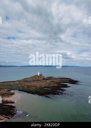 Blick auf den Mumbles Lighthouse in der Swansea Bay bei Ebbe mit Algen und Felsen im Vordergrund Stockfoto