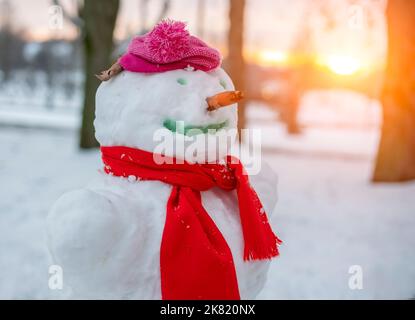 Lustiger Schneemann mit Schal und Tasse bei Sonnenschein Stockfoto