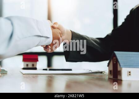 Immobilienmakler schütteln die Hände mit Kunden nach der Unterzeichnung von Dokumenten Stockfoto