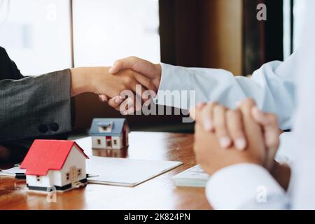 Immobilienmakler schütteln die Hände mit Kunden nach der Unterzeichnung von Dokumenten Stockfoto