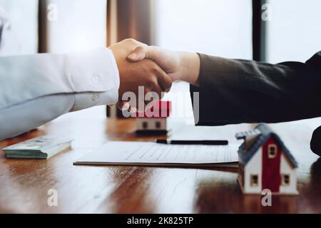 Immobilienmakler schütteln die Hände mit Kunden nach der Unterzeichnung von Dokumenten Stockfoto