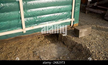 Entladung einer Bad-Sauna durch den Manipulator auf der Basis durch Arbeiter. Installation einer Bad-Sauna auf dem Territorium. Stockfoto