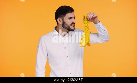 Unzufriedener Mann im weißen Hemd mit stinkenden Socken isoliert auf Gelb Stockfoto