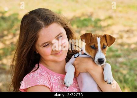 Nettes Kind umarmt Jack Russel Terrier Welpe Stockfoto