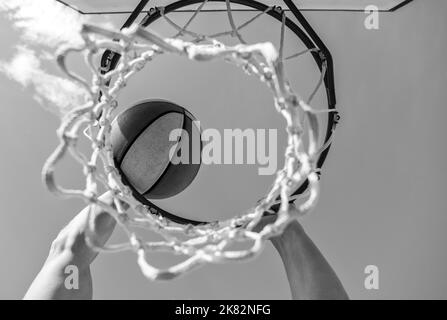 Guy dunking Basketball Ball durch Netzring mit Händen, Ziel Stockfoto