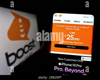 Person, die das Smartphone mit der Website des US-Telekommunikationsunternehmens Boost Mobile vor dem Logo auf dem Bildschirm hält. Konzentrieren Sie sich auf die Mitte des Telefondisplays. Stockfoto