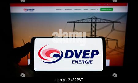 Person mit Mobiltelefon und Logo des niederländischen Energieunternehmens DVEP Energie auf dem Bildschirm vor der Business-Webseite. Konzentrieren Sie sich auf die Telefonanzeige. Stockfoto