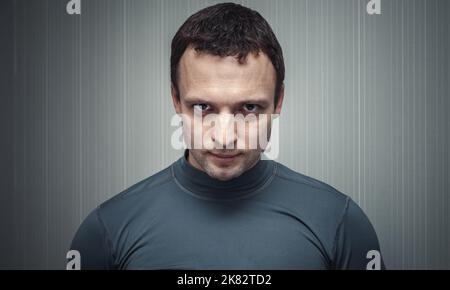 Porträt eines ernsthaften jungen erwachsenen europäischen Mannes in grauer Sportkleidung Stockfoto