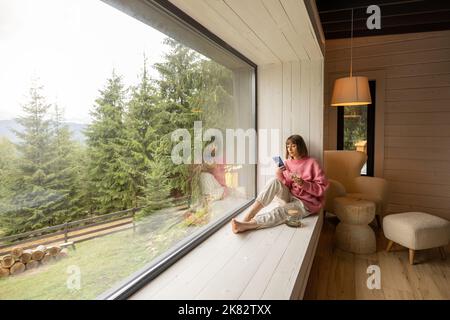 Frau ruht im Haus mit Panoramablick auf die Berge Stockfoto